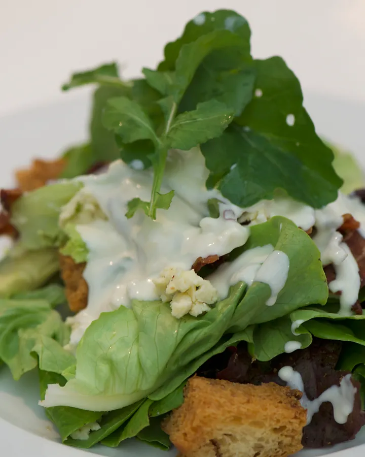Salad of fresh leaves with bacon, blue cheese dressing, avocado and croutons